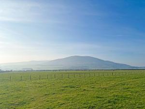 a fence in a field with a mountain in the background at Lapwing Lodge - Uk51640 in Carsethorn