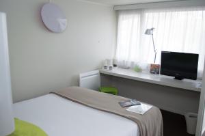 Habitación con cama y escritorio con TV. en Campanile Villeneuve-Sur-Lot, en Pujols Lot et Garonne