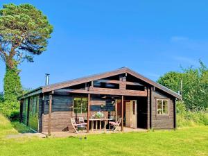 a wooden cabin with a table and chairs in a field at Skylark Lodge - Uk51678 in Carsethorn