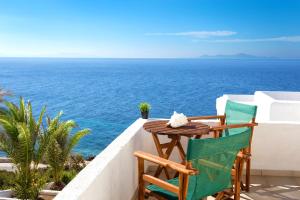 einen Tisch und Stühle auf einem Balkon mit Meerblick in der Unterkunft Pahivouni Studios & Suites in Donousa