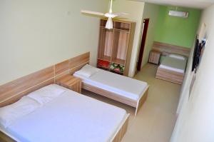 um pequeno quarto com 2 camas e uma janela em Hotel Maranhão em Ourinhos