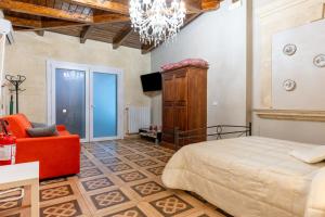 a bedroom with a bed and a chair and a chandelier at B&B Le Carrube in Sava