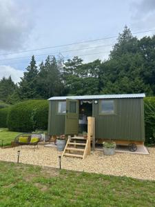 a green tiny house in a yard at Shepherds Hut in Shropshire with Swimming Pool in Shifnal
