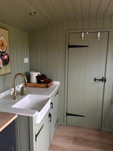 a kitchen with a sink and a door at Shepherds Hut in Shropshire with Swimming Pool in Shifnal +17 photos