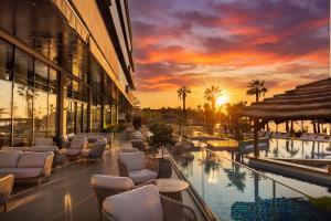a hotel patio with chairs and a pool at sunset at Liberty S Hotel in Novalja