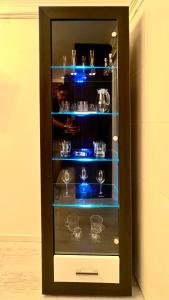 a black display cabinet with glasses in it at Escapist Apartments in Niš