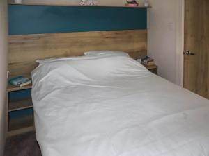 a white bed with a wooden headboard in a room at Birch 3 - Ukc8216 in Pendine