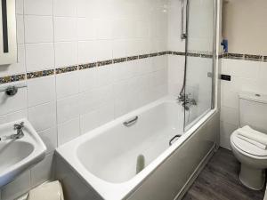 a bathroom with a tub and a toilet and a sink at Bramling Apartment - Uk49302 in Woolfardisworthy