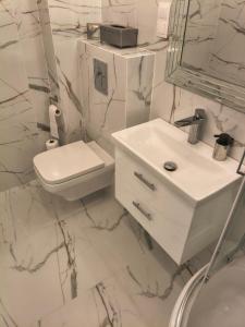 a white bathroom with a toilet and a sink at Apartament przy Matce Polce in Łódź