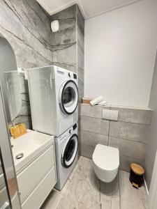 a bathroom with a washing machine and a toilet at Marigold Apartment Łódź in Łódź +8 photos