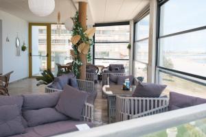a living room with a couch and tables and windows at Alessio Hotel Residence in Costinesti