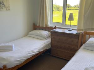 a bedroom with two beds and a dresser and a window at Holly Apartment - Uk49299 in Woolfardisworthy