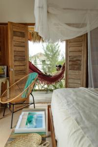 a bedroom with a bed and a window with a hammock at Yvytu - Ohana Bungalow in Tatajuba