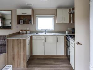 a kitchen with white cabinets and a sink at Acorn 1 - Ukc8213 in Pendine