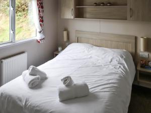 a bedroom with a white bed with towels on it at Acorn 1 - Ukc8213 in Pendine