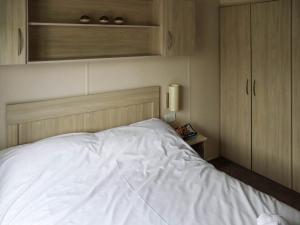 a bedroom with a white bed and wooden cabinets at Acorn 1 - Ukc8213 in Pendine +3 photos