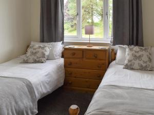 a bedroom with two beds and a dresser with a window at Sycamore Apartment - Uk49305 in Woolfardisworthy