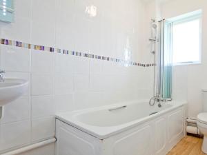 a white bathroom with a tub and a sink at Sycamore Apartment - Uk49305 in Woolfardisworthy