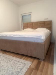 a large bed in a bedroom with a wooden headboard at Apartman Ana in Neum