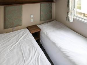 two twin beds in a room with a window at Birch 1 - Ukc8214 in Pendine +2 photos