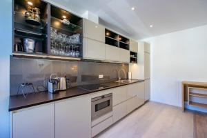 a kitchen with white cabinets and stainless steel appliances at Les Variétés in La-Roche-en-Ardenne
