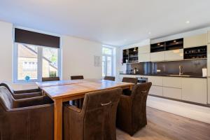 a kitchen with a wooden table and leather chairs at Les Variétés in La-Roche-en-Ardenne