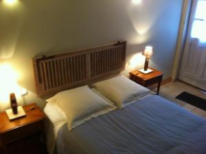 a bedroom with a large bed with two tables and two lamps at La Ferme Des Vignes in Hotot-en-Auge