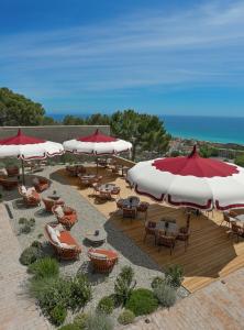 a patio with tables and chairs and umbrellas at Resort Casa del Monte 1553 in Albenga