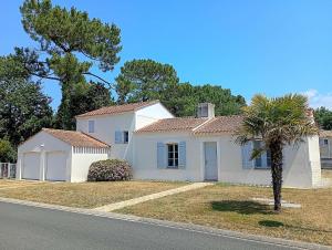 a white house with a palm tree in front of it at Villa l Albatros - Coex in Coëx