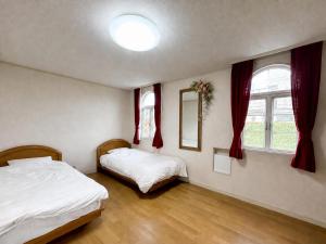a bedroom with two beds and two windows at ホワイトホテル鎌倉 in Kamakura
