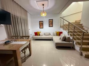 a living room with a couch and a stair case at Triplex résidence tilel chott mariem in Sousse