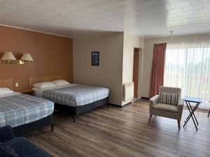a hotel room with two beds and a chair at Le Campagnard in Matane