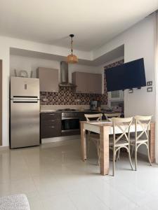 a kitchen with a refrigerator and a table with chairs at Triplex résidence tilel chott mariem in Sousse