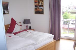 Un dormitorio con una cama con sábanas blancas y una ventana. en Marina 68/70, en Cuxhaven