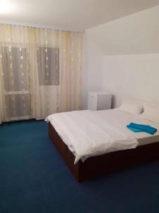 a bedroom with a bed with white sheets and a window at Casă Bubu in Cacica