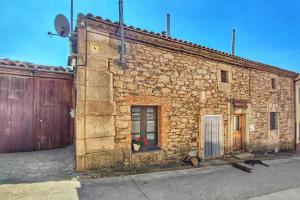 an old stone building with a door and a fence at Hotel Rural Bermellar in Bermellar