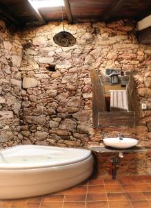 a stone bathroom with a tub and a sink at Hotel Rural Bermellar in Bermellar