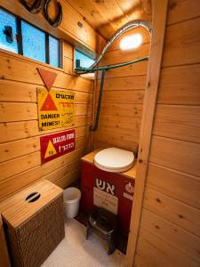 a bathroom with a toilet in a wooden cabin at Green Bus in Beit Hillel