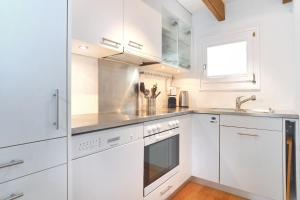 a white kitchen with white cabinets and a sink at Apartment Nussbaum - GRIWA RENT AG in Grindelwald