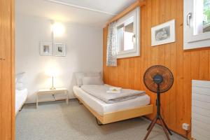 a small bedroom with a bed and a fan at Apartment Nussbaum - GRIWA RENT AG in Grindelwald