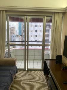 a room with a bed and a large window at Apto com localização privilegiada e piscina - Charmoso e completo in Recife
