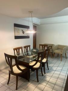 a dining room with a glass table and chairs at Apto com localização privilegiada e piscina - Charmoso e completo in Recife