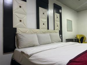 a bedroom with a large bed with white pillows at Smarthome Hotel in Benin City