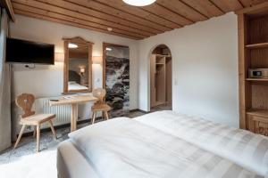 a bedroom with a bed and a desk and a tv at Haus Wildschütz by Hotel Tirolerhof in Tux +19 photos