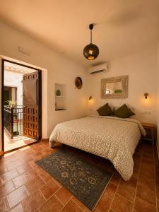a bedroom with a bed and a door to a balcony at Encanto Guesthouse in Canillas de Aceituno