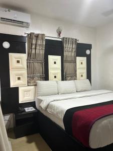 a bedroom with a large bed and curtains at Smarthome Hotel in Benin City +3 photos