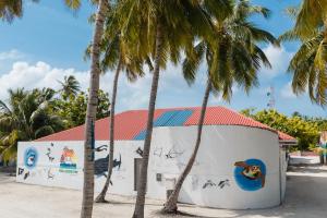 a building with palm trees in front of it at Feeali Buddies Inn in Maldive Islands