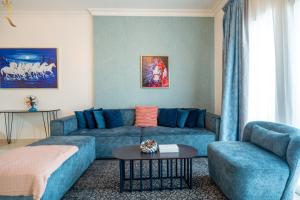 a living room with a blue couch and a table at Yas Island 1BR - Coastal Blue Haven in Abu Dhabi +111 photos