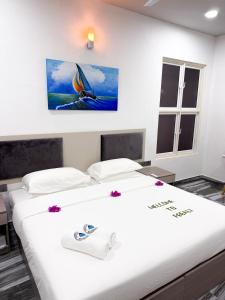 a room with two beds and a painting on the wall at Feeali Buddies Inn in Maldive Islands +5 photos
