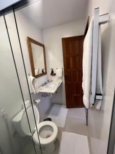 a bathroom with a toilet and a sink and a mirror at Jardim Secreto - Itaipava in Itaipava